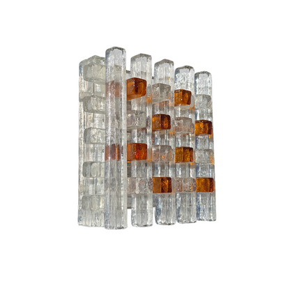 A modern wall-mounted light fixture featuring clear glass rectangular blocks with amber-orange translucent inserts, shown against a plain white background.