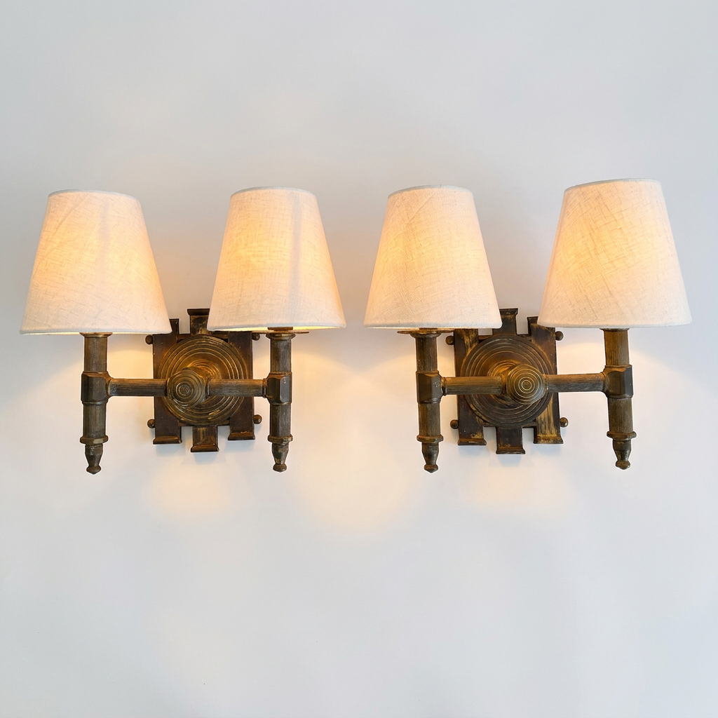 A pair of industrial-style wall sconces with dark bronze metal frames and four tapered off-white fabric shades, shown mounted on a plain light gray wall