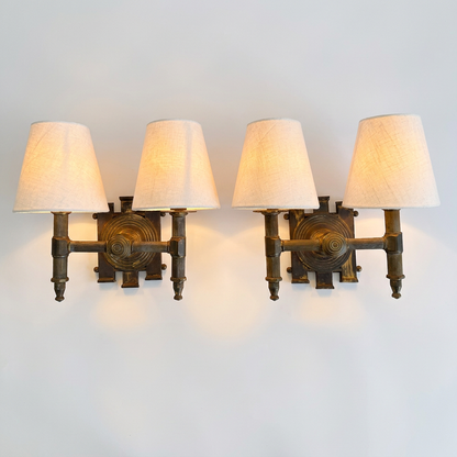 A pair of industrial-style wall sconces with dark bronze metal frames and four tapered off-white fabric shades, shown mounted on a plain light gray wall