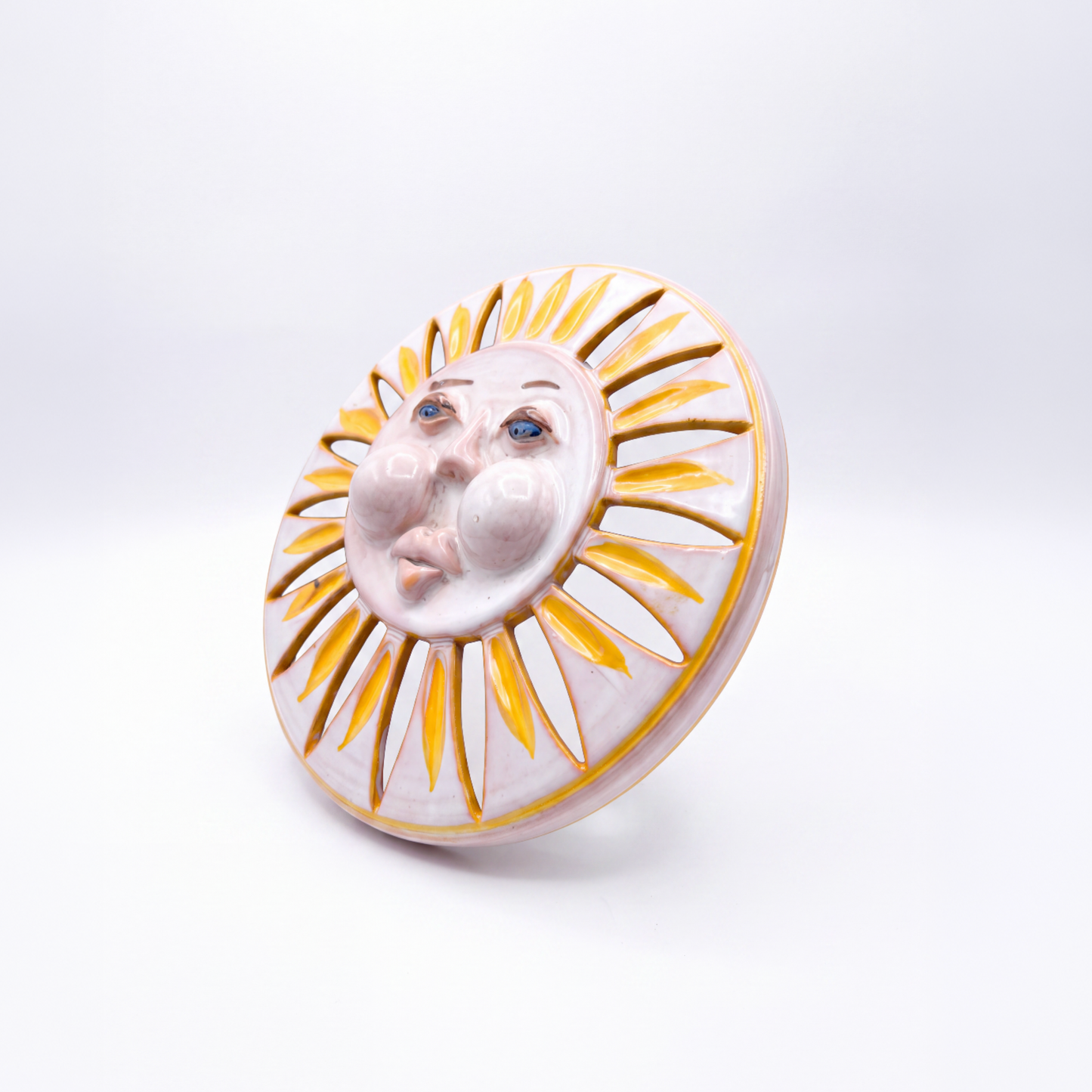Close-up of sun face with enlarged cheeks and cutout ray apertures on 1960s Italian ceramic light